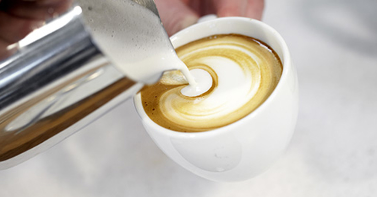 Skummad mjölk som hälls i kaffe Skummad mjölk som hälls i kaffe